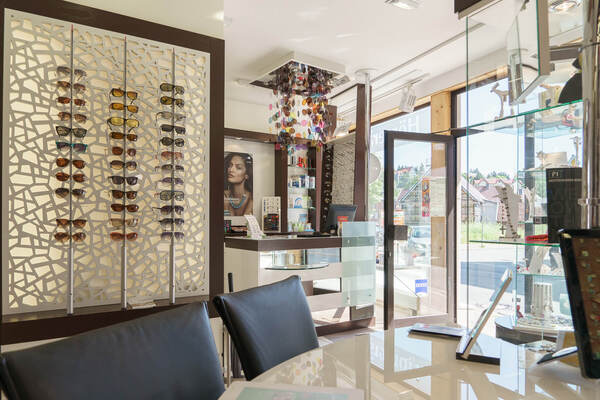 Modernes Optikergeschäft mit Sonnenbrillenauswahl, Beratungstheke und heller Einrichtung.