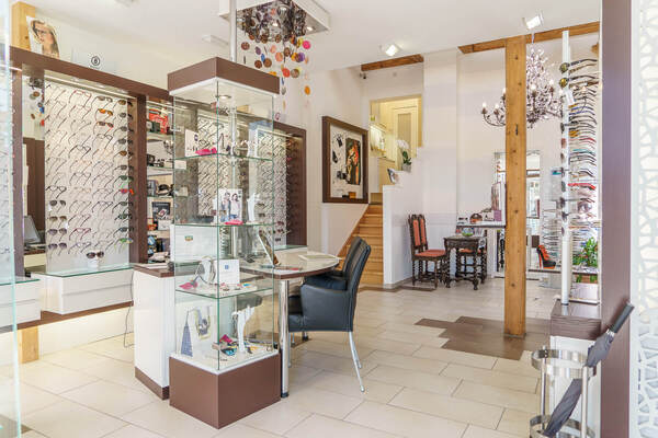 Modernes Optikergeschäft mit großer Auswahl an Brillen, Beratungstisch und stilvoller Einrichtung.