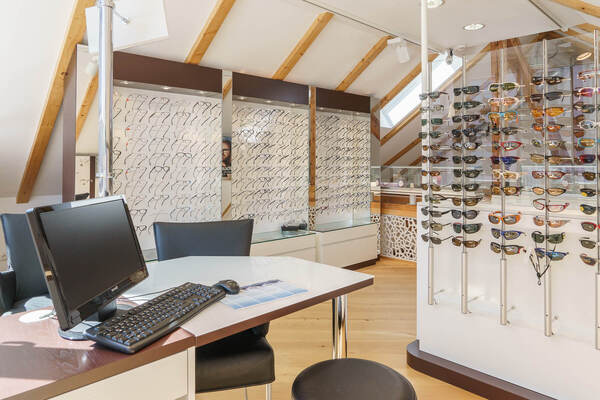 Modernes Optiker-Geschäft mit vielfältiger Brillenauswahl und Beratungsplatz.